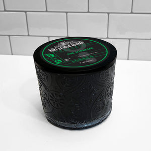 Black Marquis glass jar with flourish pattern, white soy wax candle. Black lid with label for The Supreme candle. 